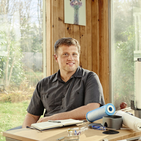 Dr. Eric Roy seated at his desk with Hydroviv water filter refills on his desk.
