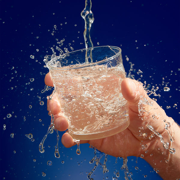 A photo of clean water pouring into a glass. It's imposed against a dark blue background.