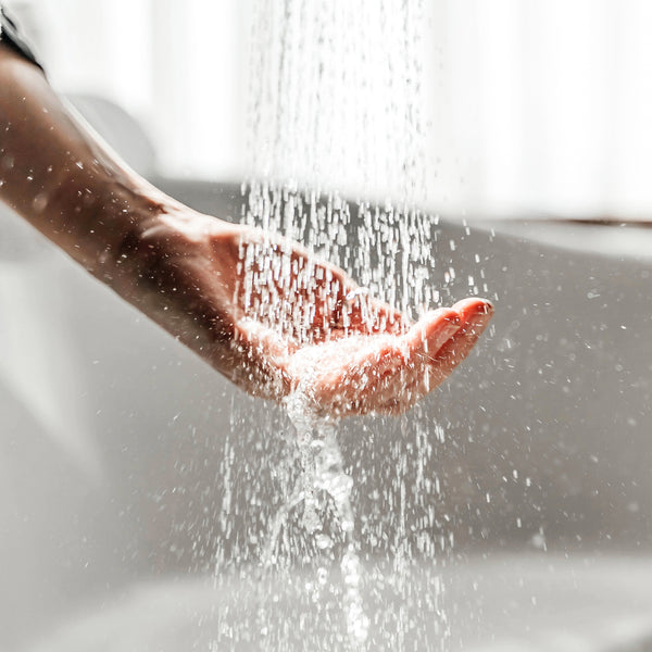Photo of a woman's hand under shower water flow