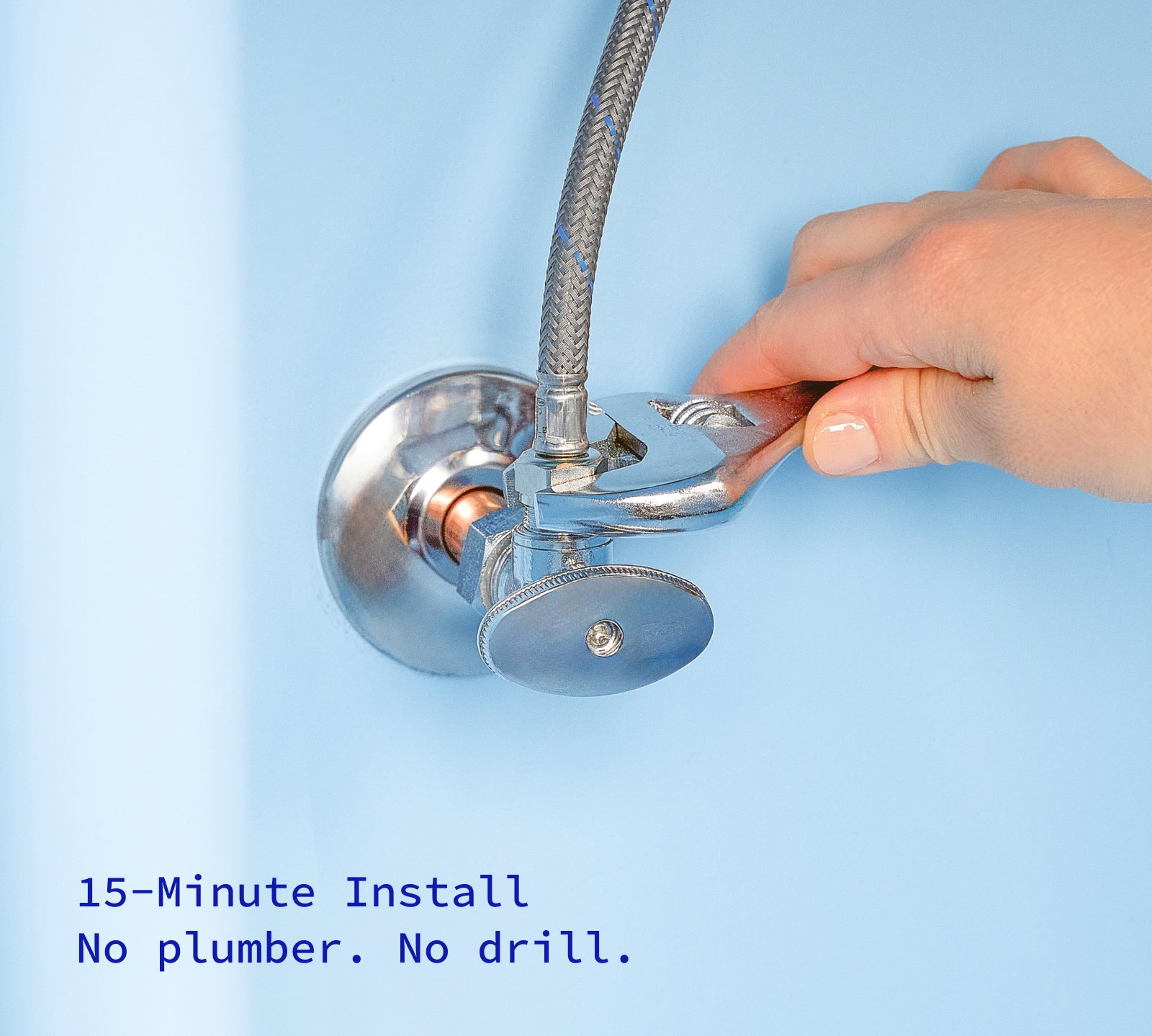 Hand with wrench turning off water inside kitchen cabinet.