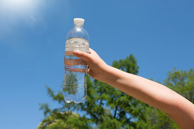Child holding plastic water bottle with blue background