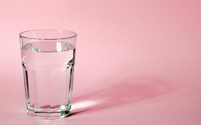 glass of drinking water with pink background