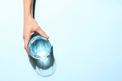person holding glass of water on blue background