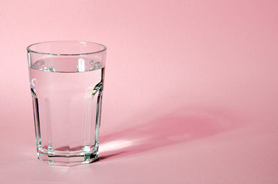 Glass of water with pink background