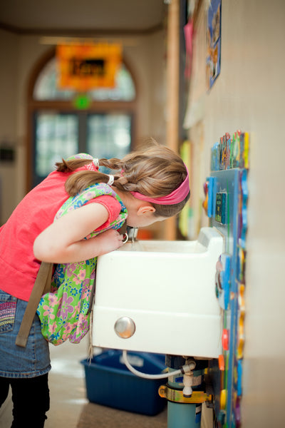 girl drinking out of water fountain at school