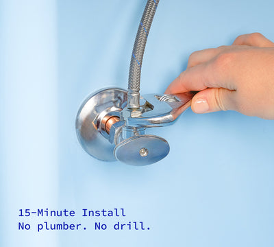 Hand with wrench turning off water inside kitchen cabinet.